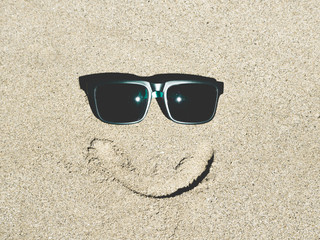 Fototapeta na wymiar Summer concept with sunglasses smiling on sand beach.
