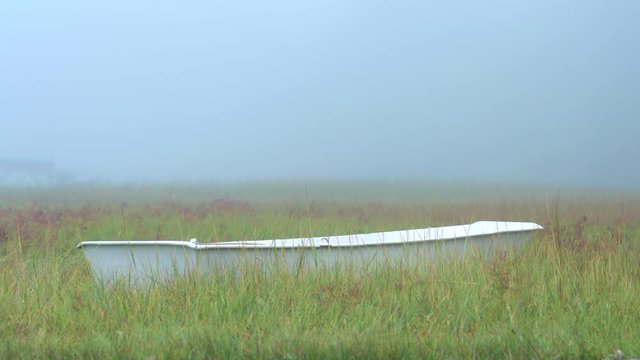 Old wooden rowboat dinghy beached in dune grass on Cape Cod.