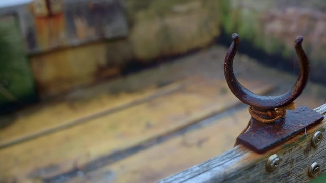 Camera pans to reveal tight closeup of rusty old oarlock on a wooden rowboat. Cobwebs.