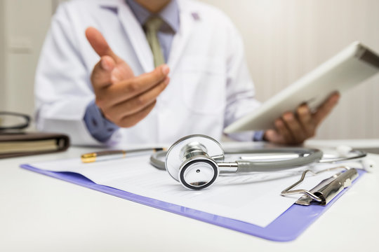 Medicine and health care concept. Close-up of stethoscope is lying on the clipboard near a doctor consults patient.