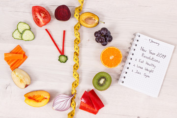 Fototapeta na wymiar Clock made of fruits and vegetables and centimeter, new year resolutions of healthy lifestyles