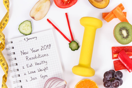 Goals for new year 2019 in notepad, fruits with vegetables in shape of clock, tape measure and dumbbell