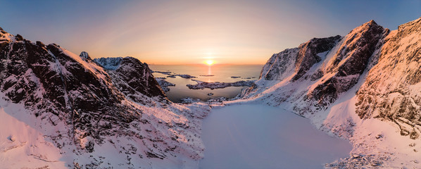 Panorama aerial view of mountain range with ice lake in valley with arctic ocean at sunset