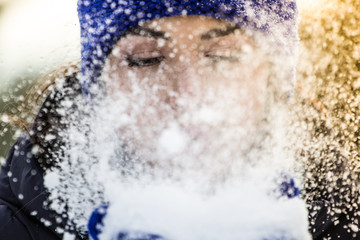 beautiful brunette blows snow from her palms