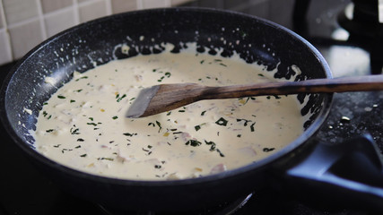 spaghetti carbonara in frying pan with wooden spatula