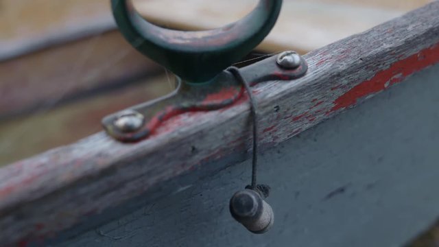 Tight closeup of rusty old oarlock on a wooden rowboat. Cobwebs. Camera tilts up.