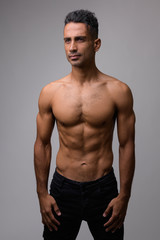Portrait of young muscular Persian man thinking shirtless