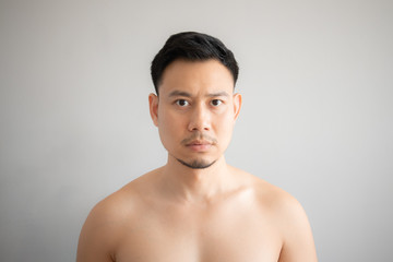 Serious and stress face of Asian man in topless portrait isolated on gray background.