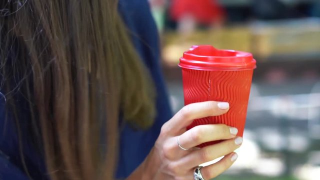 Woman Outdoors Holds A Red Plastic Cup In Her Hand.