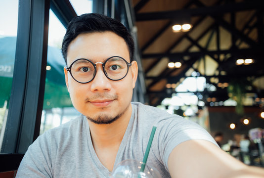 Man with glasses selfy himself drink coffee in the cafe.