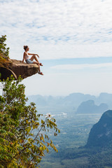 Young girl traveler  sitting on a cliff