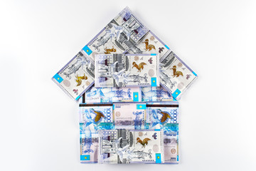 Tenge. Kazakh money in the shape of a house on a white background. Real estate loan concept.