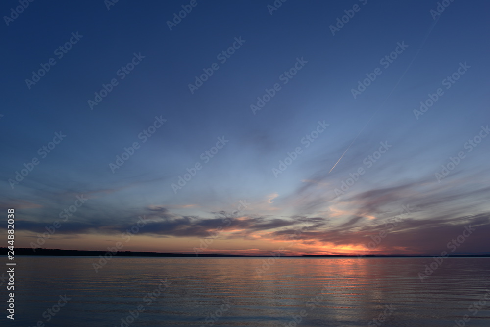 Wall mural glowing sunlight in the clear blue twilight sky in the silence of the summer evening before nightfal