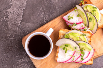 Tasty toasts with radish, avocado and sprouts, cup of coffee
