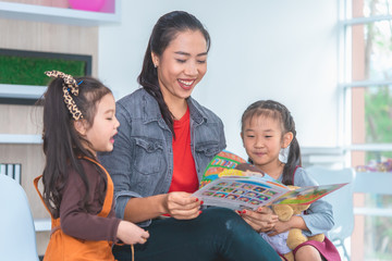 Teacher is reading story book to kindergarten students laughing