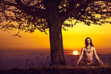 Yogi man meditating at sunset on the hills. Lifestyle relaxation emotional concept spirituality harmony with nature