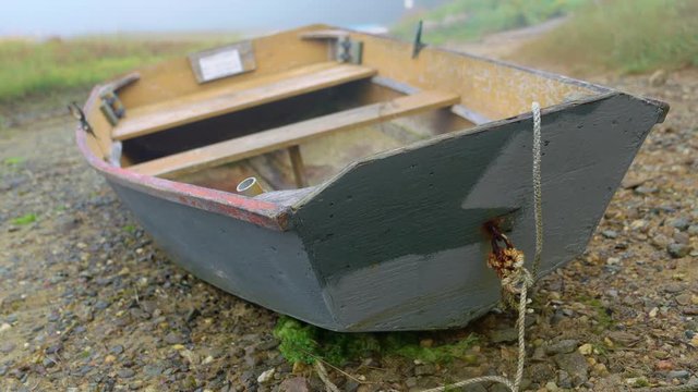 Classic shot of nice wooden rowboat dinghy beached on rocky shore.