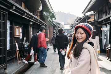 Happy Asian Girl with pink overcoat in Takayama old town, Gifu, Japan during cold weather in winter.