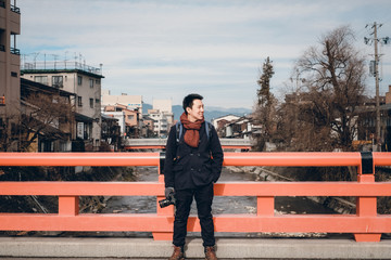 Beautiful Asian Girl with pink overcoat photo at Nakabashi Bridge (red colour) near hida takayama old town, Gifu, Japan on winter.
