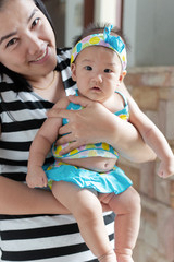 asian woman holding baby cute swimming suite in her arms