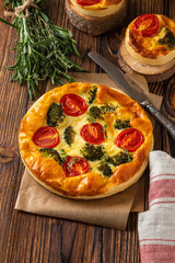 Vegetable pie with broccoli, peas, thyme. tomatoes and cheese on wooden background. Copy space.