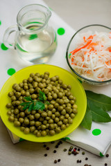 green peas decorated with a sprig of parsley in a yellow plate, fresh cabbage salad and a glass...