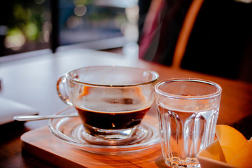 Cup of coffee on table with smoke in the morning at cafe. Vintage filter