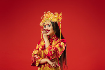 Chinese traditional graceful woman at studio over red background. Beautiful girl wearing national costume. Chinese New Year, elegance, grace, performer, performance, dance, actress, dress concept