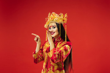 Chinese traditional graceful woman at studio over red background. Beautiful girl wearing national costume. Chinese New Year, elegance, grace, performer, performance, dance, actress, dress concept