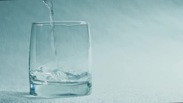 Water pour into a glass on a white background