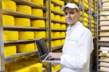 worker with a laptop in his hands at the cheese warehouse