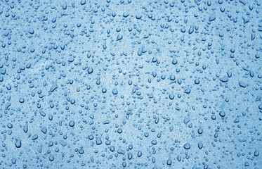 Water drops on car surface in navy blue tone.