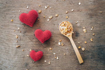 Heart made of red yarn with granola  on wooden background. Valentine day concept.