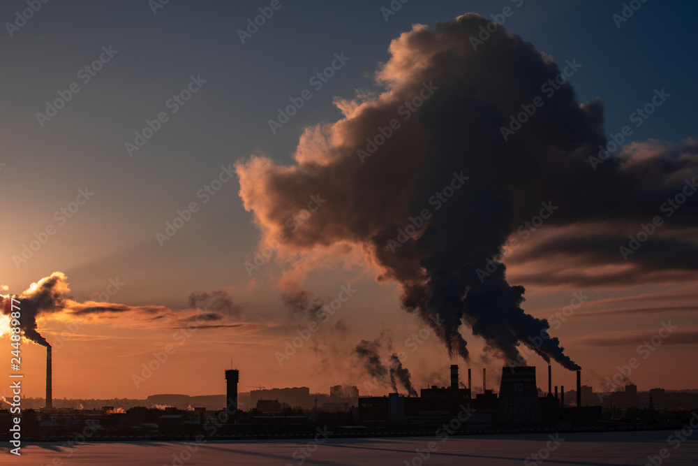 Wall mural steaming cooling towers and smoking industrial stacks against sunset gradient sky