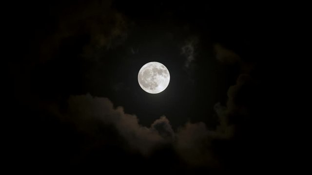 Full moon in night sky surrounded by scary clouds and dark black sky