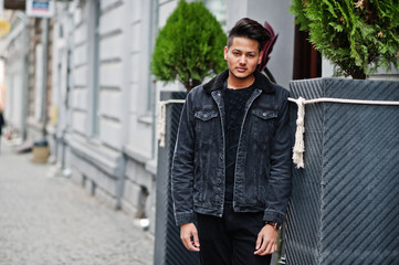 Handsome and fashionable indian man in black jeans jacket posed outdoor.