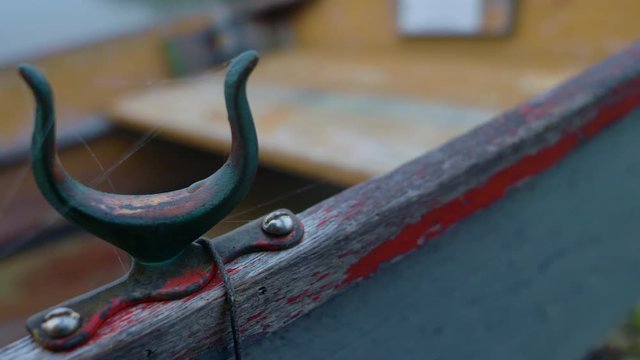 Tight closeup of rusty old oarlock on a wooden rowboat. Cobwebs. Camera pans left.