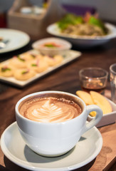 White Cup of coffee latte art and food  on table wooden background.