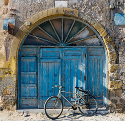 Old blue wrabic door in Morocco (Marrakesh) and bicycle. Traditional oriental style and design in Muslim countries