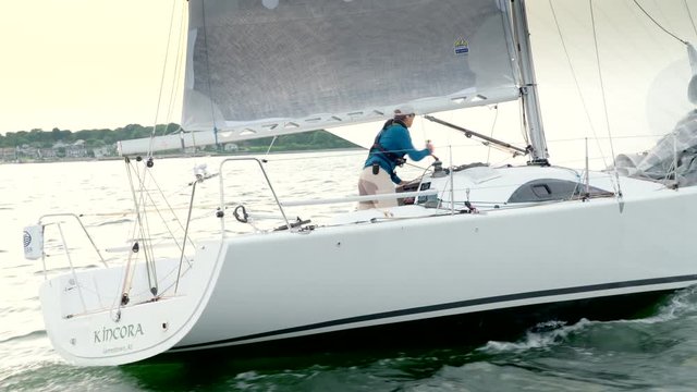Professional solo sailor sailing on the ocean in a racing sailboat.  Shot from chase boat slightly behind.