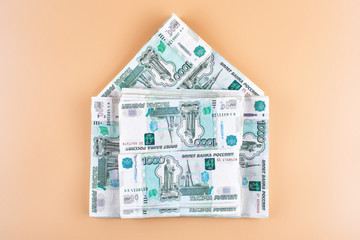 Rubles. Russian money in the shape of a house on a beige background. Real estate loan concept