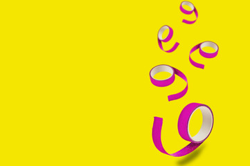 Falling rolls of violet sticky tapes on yellow background with copy space for your text