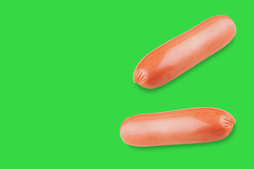 Pair of prepared long sausages on green background with copy space for your text
