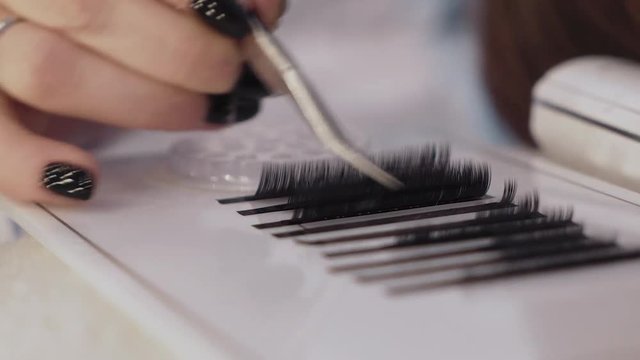 artificial eyelashes, the hand holds tweezers and holds on the eyelashes