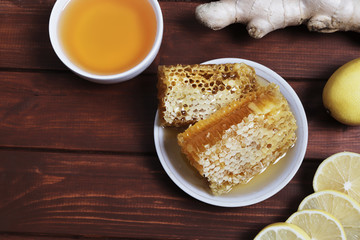 Traditional medicine. Honey and bee honeycombs. Ginger and lemon on the wooden table. Place for text. Top view.