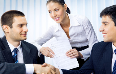 Three businesspeople handshaking with document