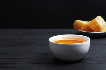 Traditional medicine. Honey and bee honeycombs on a black wooden background. Healing tea. Ingredients for tea. Honey for tea. Ginger and lemon. Copy space. Design elements