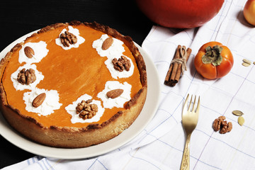Sweet pumpkin cream pie. Pie with nuts. Harvest Pumpkin pie on a black wooden background. Pears and apples. Top View. Halloween cake.
