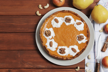 Sweet pumpkin cream pie. Pie with nuts. Harvest Pumpkin pie on a brown wooden background. Pears and apples. Top View.