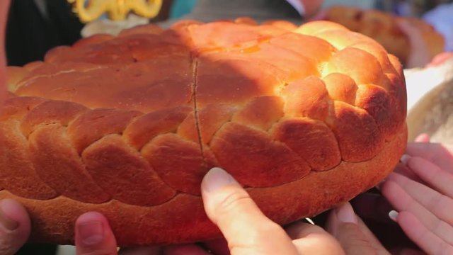 People hold a bannock bread on a holy day in front of the church. Bread in honor of the saint. It is traditionally baked bannock bread and pour the wine over it, then people eat bread in honor of sain